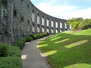 Side shot of McCraigs tower with a grassy hillside and sun streaming down