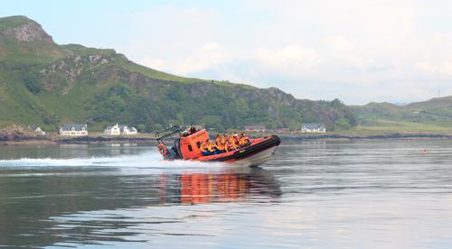 Red speedboat on water with hilly backdrop. Wildlife boat tour